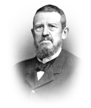 A sepia-toned portrait of a person with a beard, wearing a suit with a bow tie, facing the camera.
